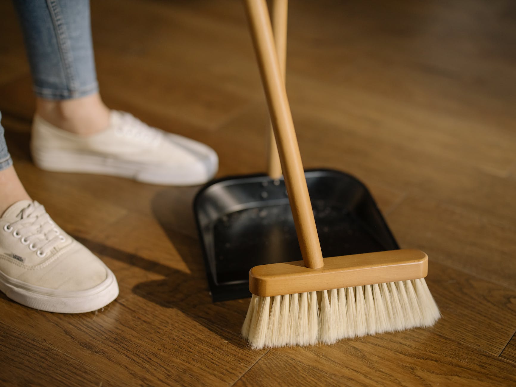 person wearing white pants and white socks standing beside brown broom